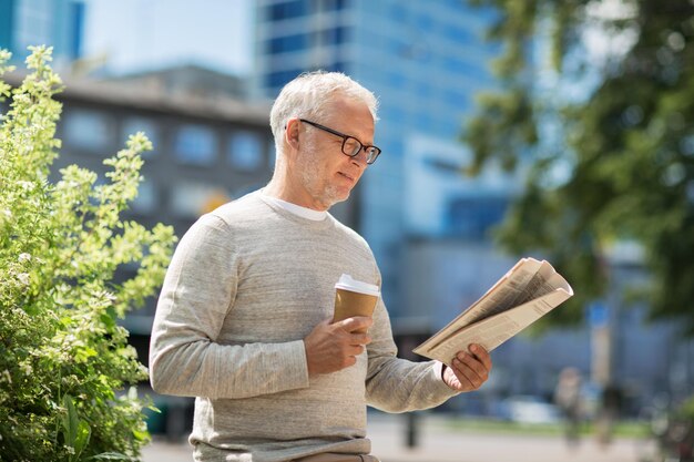 マスメディア、ニュース、人々のコンセプト – 市内で新聞を読み、コーヒーを飲む年配の男性