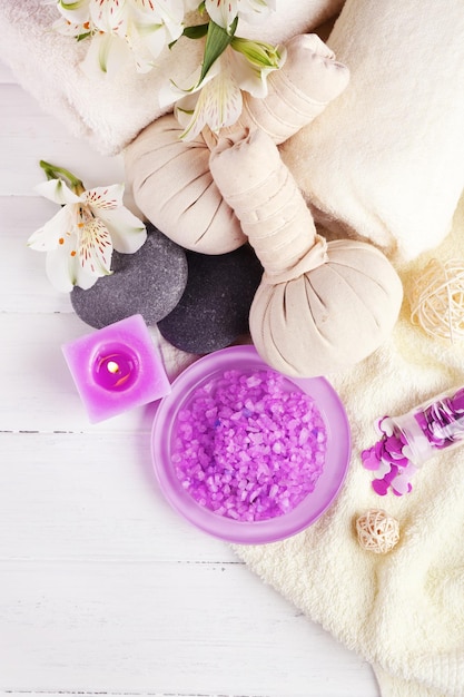 Massage bags with spa treatment and flowers on wooden table background