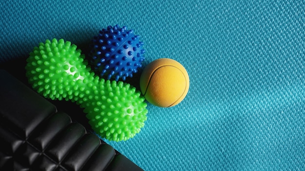 Massage ball and roller for self massage, reflexology and myofascial release, blue background. Equipment for sports, yoga, fitness