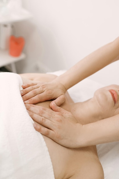 Massage and body care a woman in adulthood receives a relaxing and toning massage of the face and neck chest in the spa