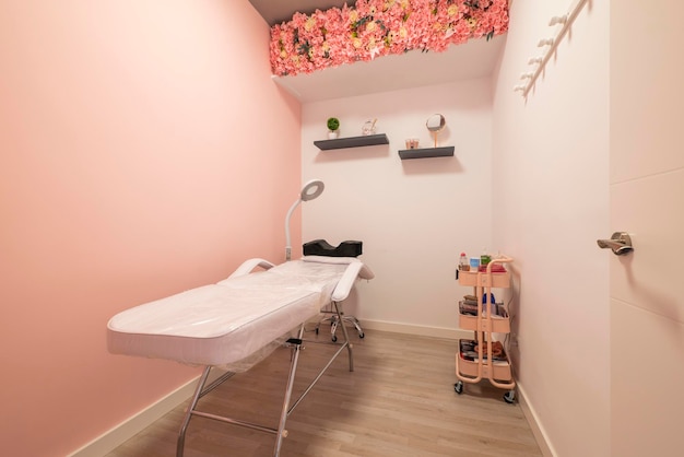 Foto cabina per massaggi con lettino pieghevole in un salone di bellezza con pareti rosa semplici