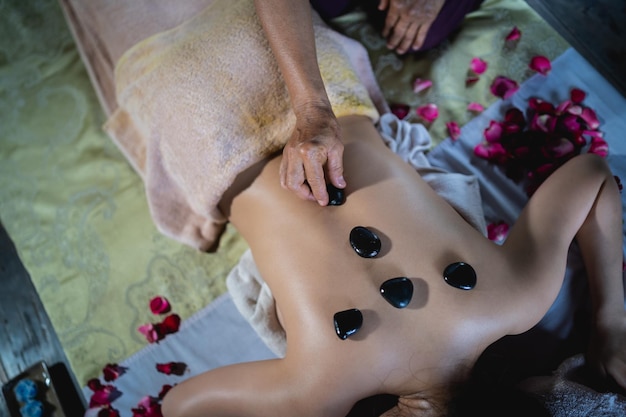 Massage en spa ontspannende behandeling van kantoorsyndroom met behulp van hot stone traditionele Thaise massagestijl Aziatische vrouwelijke masseuse die massage doet, behandelt rugpijn armpijn stress voor vrouw die moe is van het werk