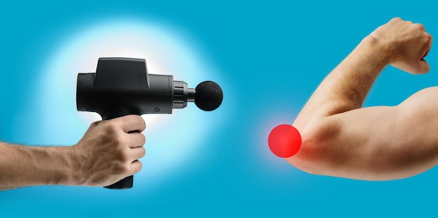 Massage gun in hand and elbow with pain point on a blue background with copy space