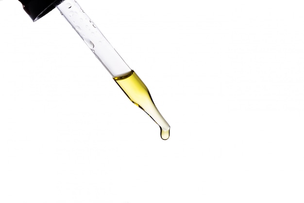 Massage oil in a glass bottle with a pipette on a white isolated background.