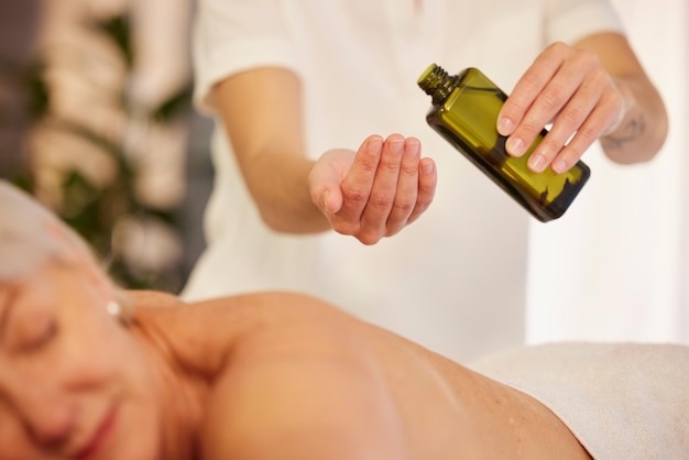 Foto olio da massaggio e un terapista con una donna in una spa per rilassarsi con un servizio benessere e cura della pelle bottiglia per le mani e una massaggiatrice con trattamento antistress per il corpo o la persona di un paziente in un hotel