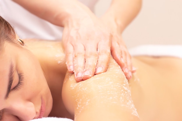 Massage and skin cleansing with a scrub. Beautiful girl gets a scrub in a spa salon. 