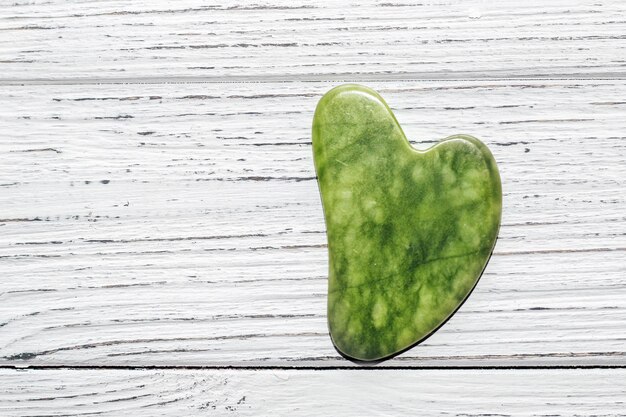 Massage stone jade gouache scraper on wooden background