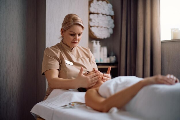 Massage therapeut die het gezicht van vrouwen massageert tijdens een spa-behandeling