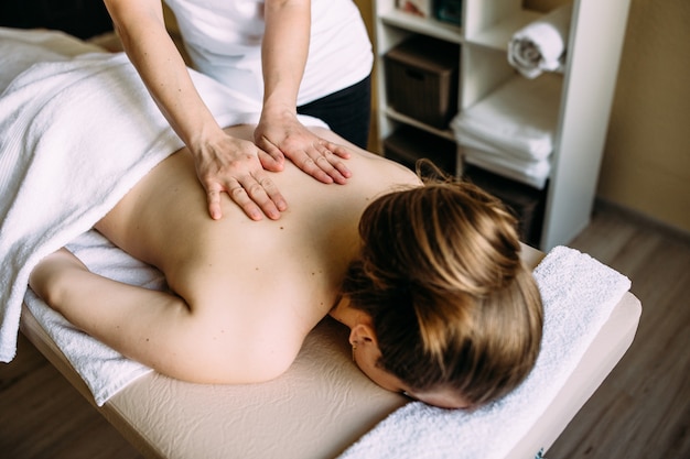 Massage therapist doing massage on the female body in the spa