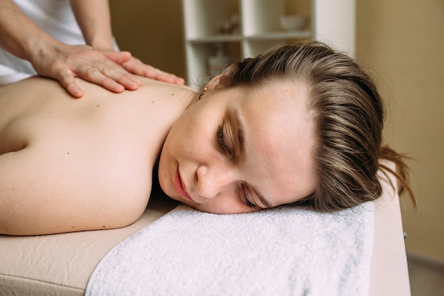 Massage therapist doing massage on the female body in the spa