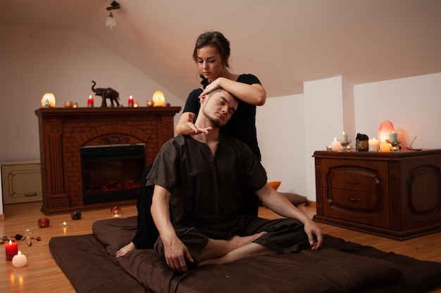 A massage therapist works with a woman in a room with a fireplace in the background.