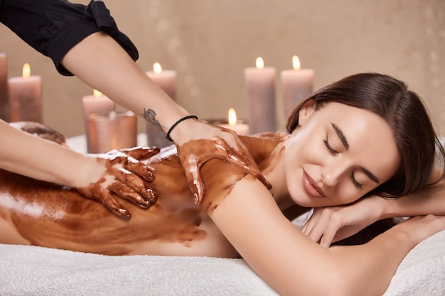 Massage with chocolate in spa on beautiful girl