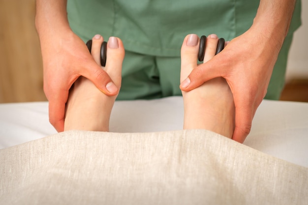 Massager doet voeten en tenen massage met rotsen tussen een vrouwelijke tenen.