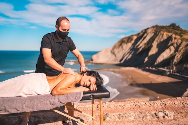 Massaggi in spiaggia sul litorale vicino al mare massaggiatrice con maschera viso