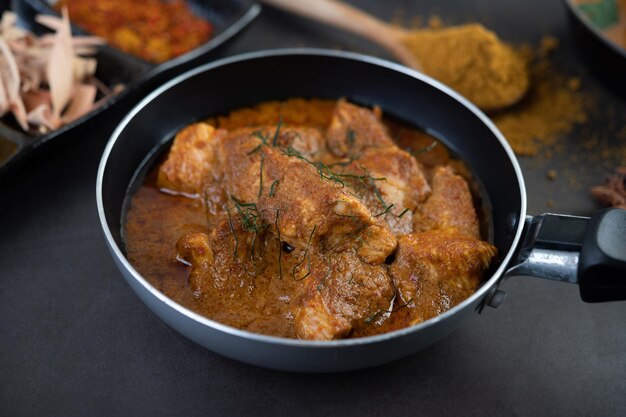 Photo massaman curry in a frying pan with spices on the cement floor