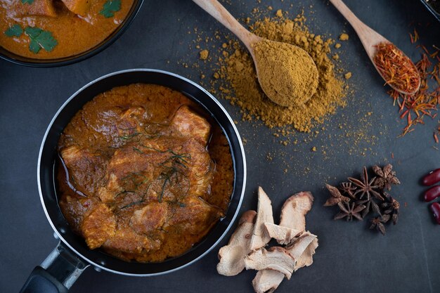 Photo massaman curry in a frying pan with spices on the cement floor