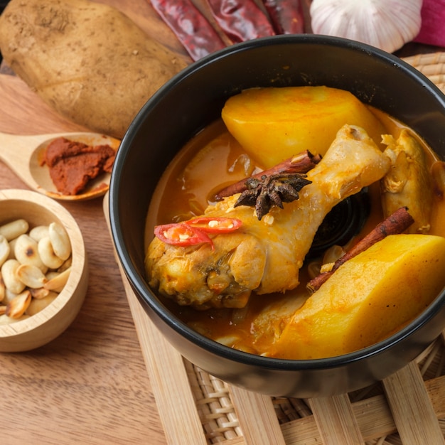 Massaman Curry With Chicken and Thai herbs with wood background texture