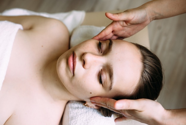 Masseur doet massage op het gezicht van een vrouw in de spa