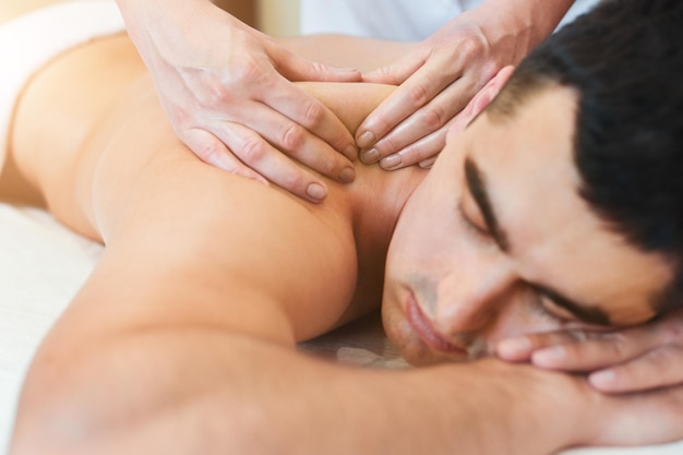 Masseur doet rugmassage op het lichaam van de man in de spa salon.