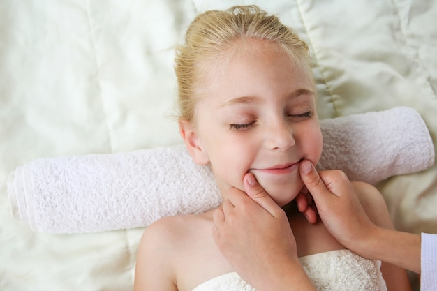 Masseur doing face massage to child.