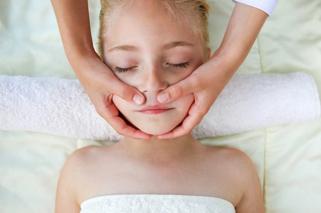 Masseur doing face massage to child.