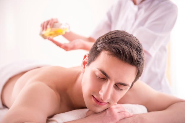 Foto massaggiatore che fa massaggio sul corpo dell'uomo con olio termale.