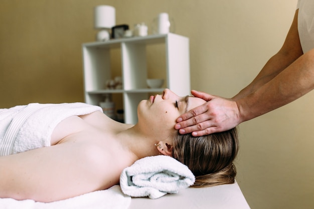 Masseur doing massage on a womans face at the spa