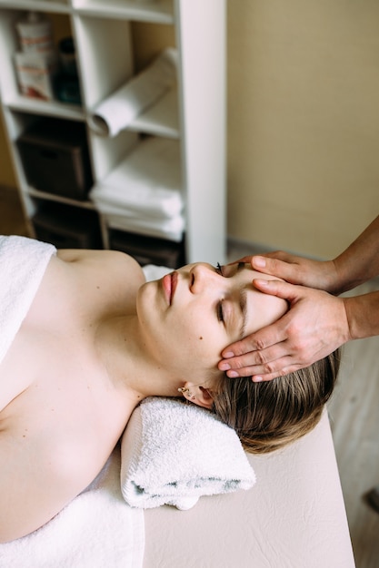 Foto massaggiatore che fa un massaggio sul viso di una donna alla spa