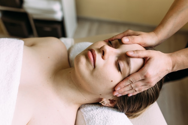 Masseur doing massage on a womans face at the spa