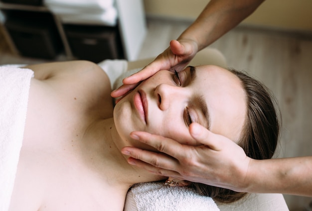 Masseur doing massage on a womans face at the spa