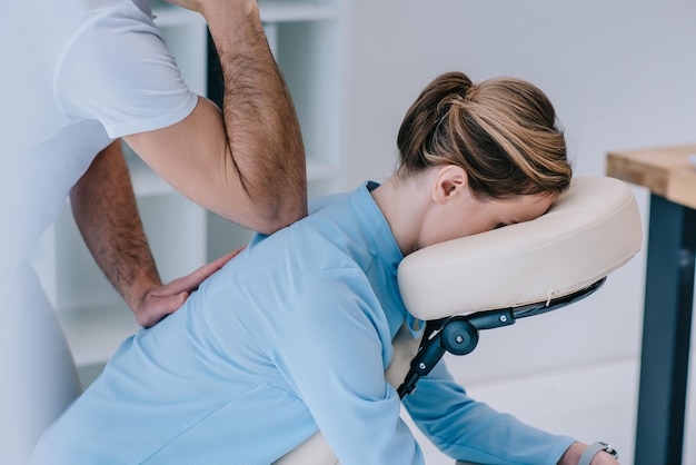 Foto massaggiatore che fa massaggi seduto per una donna d'affari