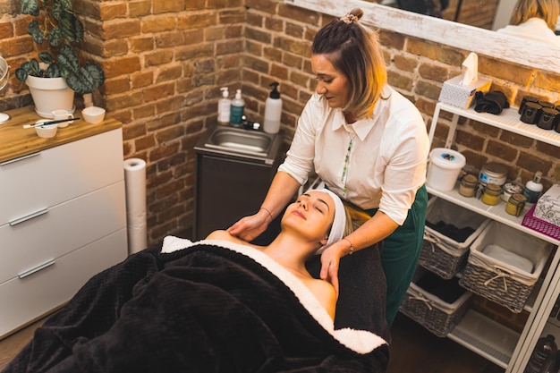 Masseur geeft ontspannende massage aan een blonde cliënt liggend op de massagetafel in de spa