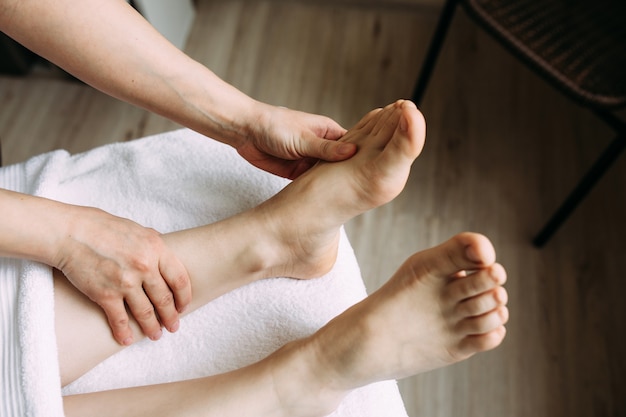 The masseur gives a massage to the female feet at the spa