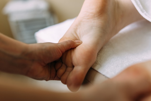 The masseur gives a massage to the female feet at the spa