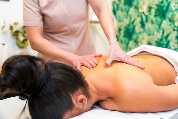 Foto massaggiatore che dà un massaggio alla schiena a una donna sdraiata su una barella