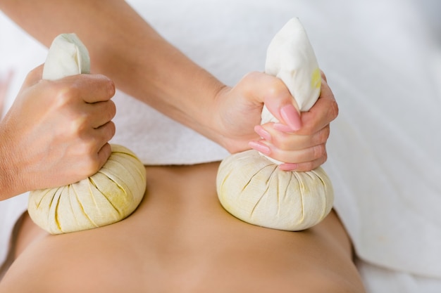 Masseur giving herbal compress massage to woman