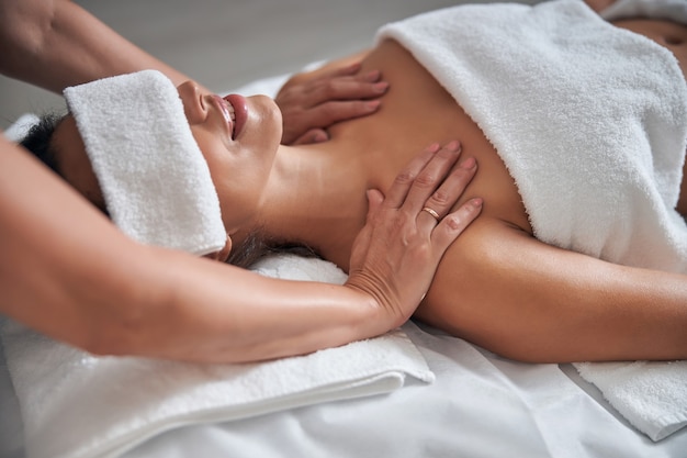 Photo masseur hands massaging female shoulders in spa salon