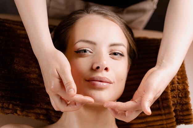 Masseur is making facial massage in spa for model with perfect skin. Beauty procedure.