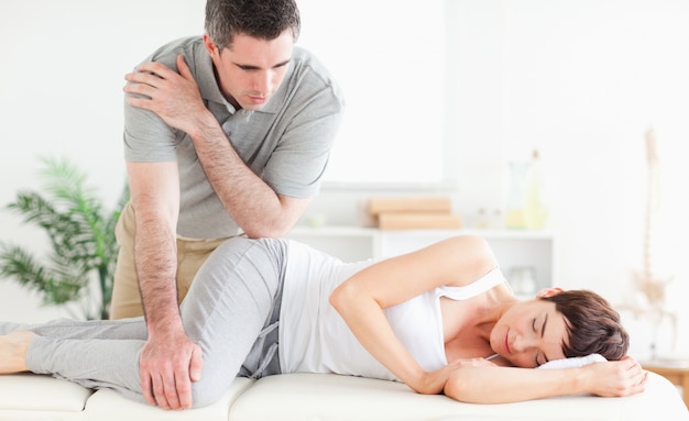 A masseur is massaging a woman's hip 