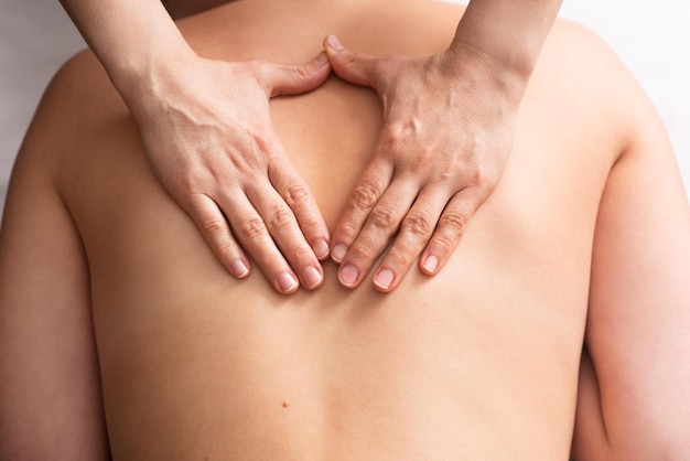 Masseur massaging back and shoulder blades of young woman on massage table Concept of massage spa treatments Closeup