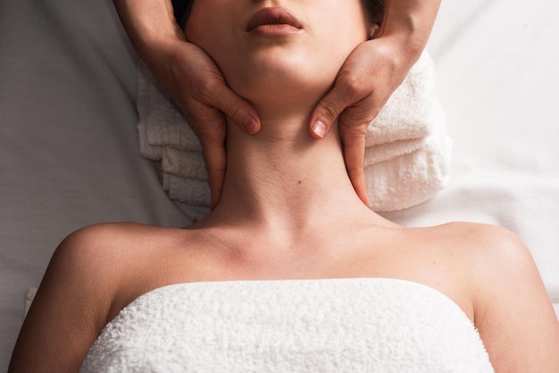 Masseur massaging decollete and neck of young woman on massage table Concept of massage spa treatments Closeup