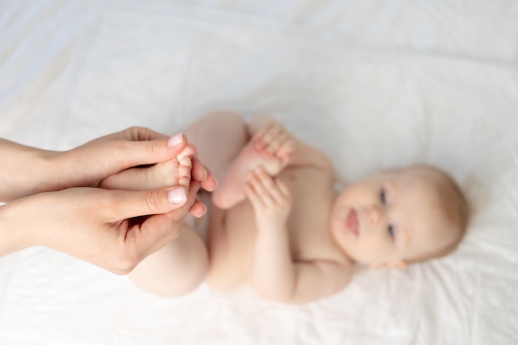 Photo masseur or mother's hands do foot massage for the baby, focus on the hands.