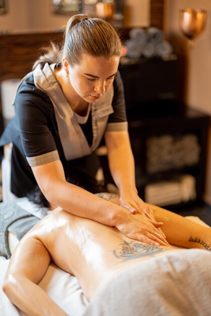 Photo masseuse applies relaxation massage to a woman at spa salon