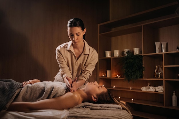 A masseuse gives a body massage to a woman in a spa center A professional masseur massages the shoulder of a girl lying in a spa center