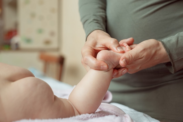 Masseuse massaging 3 months infant mother does a foot massage to a newborn baby mothers care