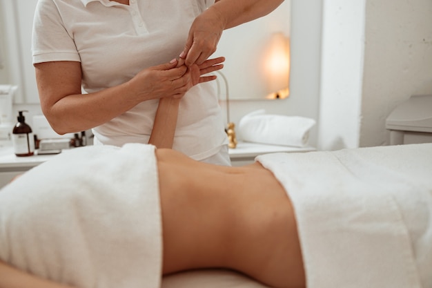 Foto massaggiatrice che massaggia la mano della donna nel salone della stazione termale