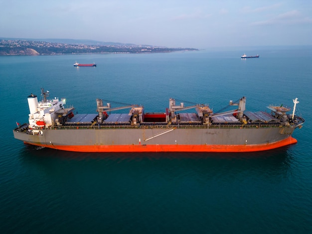 Photo a massive cargo ship wood chips carrier in the sea aerial view