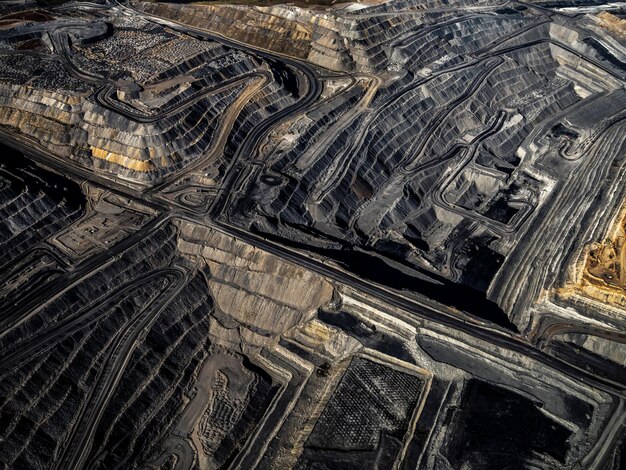 Photo a massive dirt pit with lots of coal on it and two other smaller piles