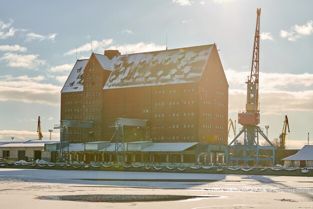 Photo massive harbor cranes in seaport. heavy load dockside cranes in port, cargo container yard, container ship terminal. business and commerce, logistics. winter industrial scene.