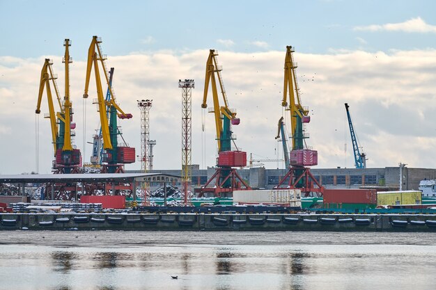 Photo massive harbor cranes in seaport. heavy load dockside cranes in port, cargo container yard, container ship terminal. business and commerce, logistics. winter industrial scene.